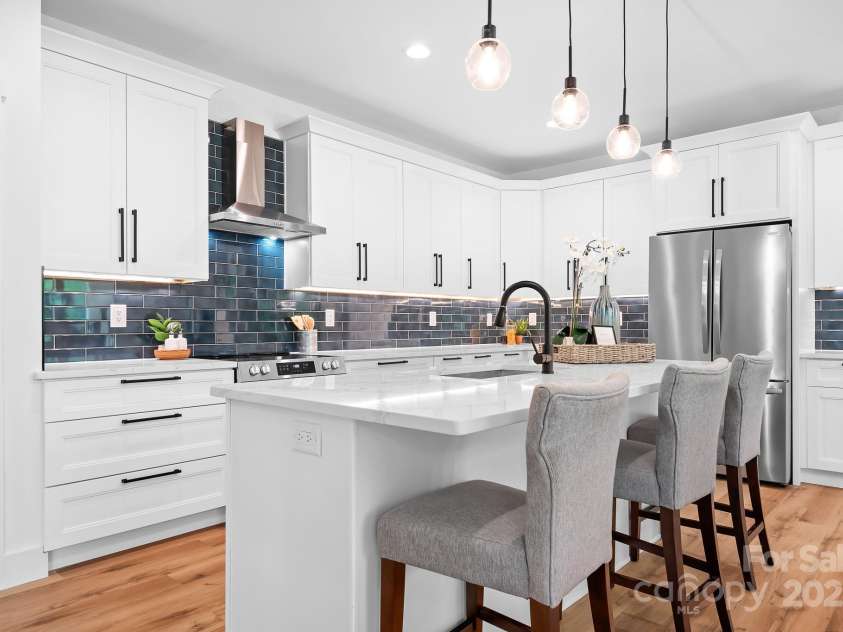 106 Arbor Drive, Waxhaw, NC 28173.  MLS# CAR4264071, YatesRealty ID 31005. Bright and elegant kitchen with striking navy tile backsplash, crisp white cabinetry, and durable quartz countertops.