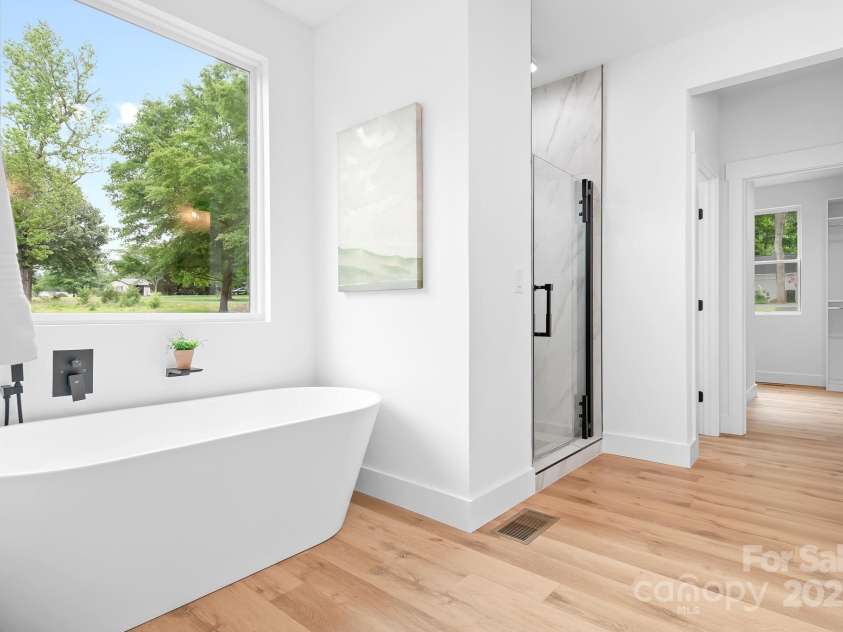 106 Arbor Drive, Waxhaw, NC 28173.  MLS# CAR4264071, YatesRealty ID 31005. Relax in this spa-like bathroom featuring a deep soaking tub with a beautiful view of the outdoors, along with a modern glass-enclosed shower and warm wood floors that add a natural touch.