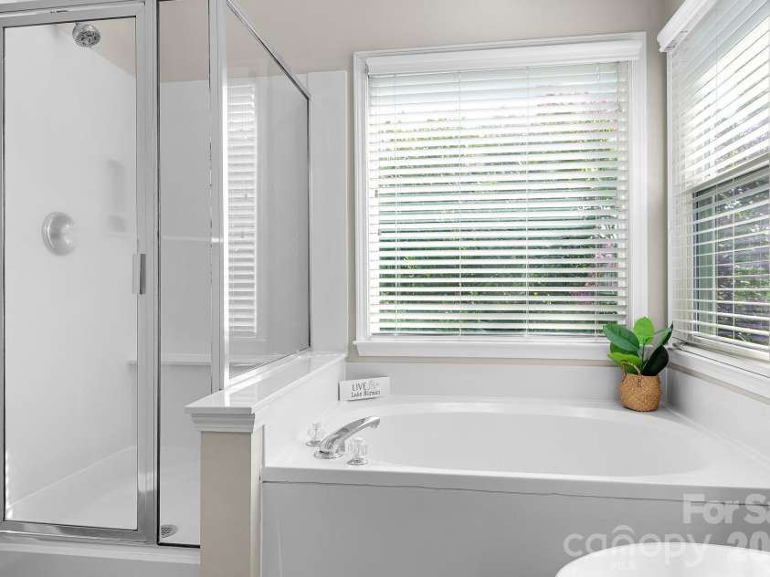 19942 Scanmar Lane, Cornelius, NC 28031.  MLS# CAR4381771, YatesRealty ID 31153. Primary Bathroom with Double sinks, upgraded mirror and lights. Soaking Tub with Corner Winows for tons of light!
