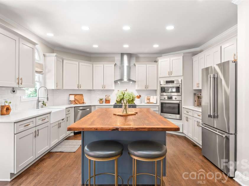 25017 Stonekirk Lane, Fort Mill, SC 29707.  MLS# CAR4383231, YatesRealty ID 31182. The renovated chef’s kitchen is a true culinary masterpiece, featuring custom shaker cabinetry, abundant storage, and a generous central island with a built-in wine fridge that serves as the heart of the home.