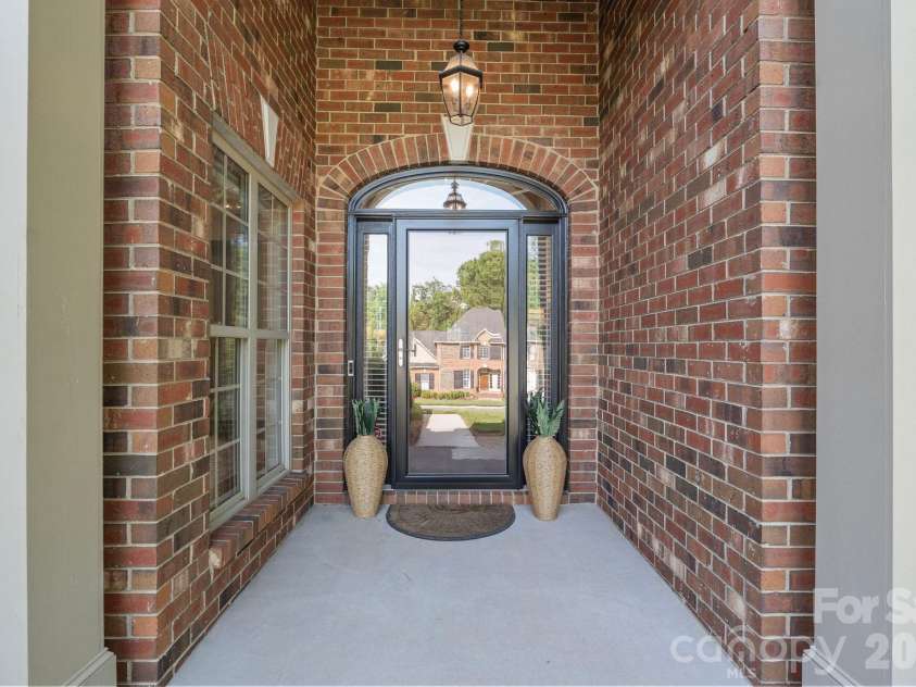 526 Ballymote Court, Matthews, NC 28104.  MLS# CAR4388258, YatesRealty ID 31207. Covered Front Entry – The inviting covered entry features soaring ceilings, brick accents, and a glass-paneled front door that creates a warm and elegant first impression.