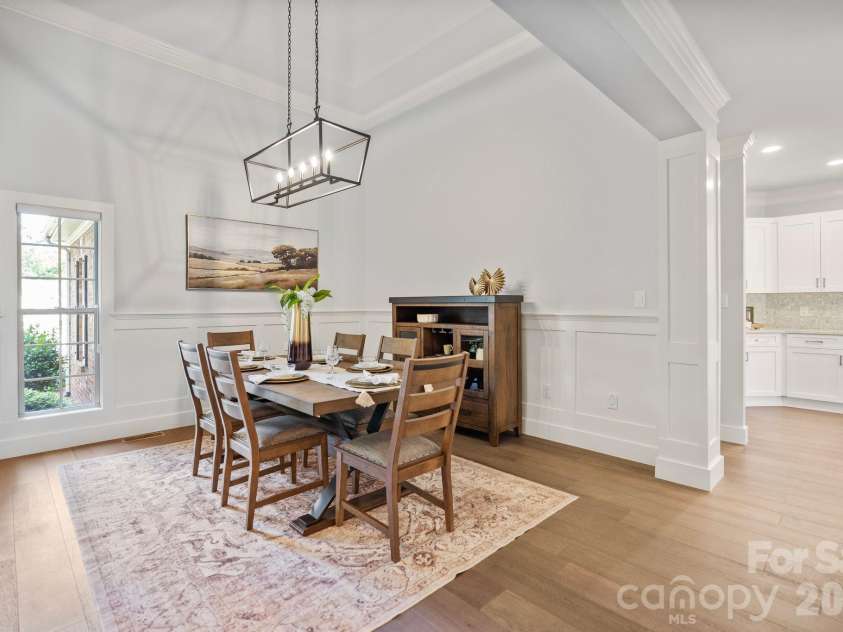 526 Ballymote Court, Matthews, NC 28104.  MLS# CAR4388258, YatesRealty ID 31207. Dining Room – Elegant formal dining room featuring soaring ceilings, extensive millwork, and a statement chandelier that creates a refined setting for gatherings. Large windows and an open flow to the main living areas 