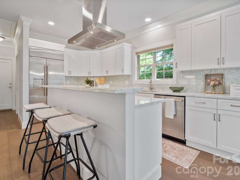 526 Ballymote Court, Matthews, NC 28104.  MLS# CAR4388258, YatesRealty ID 31207. Kitchen – A spacious center island anchors this impressive kitchen, complete with custom cabinetry, quartz countertops, a Wolf gas cooktop, Wolf wall oven, and a GE Monogram refrigerator, creating the perfect space for 
