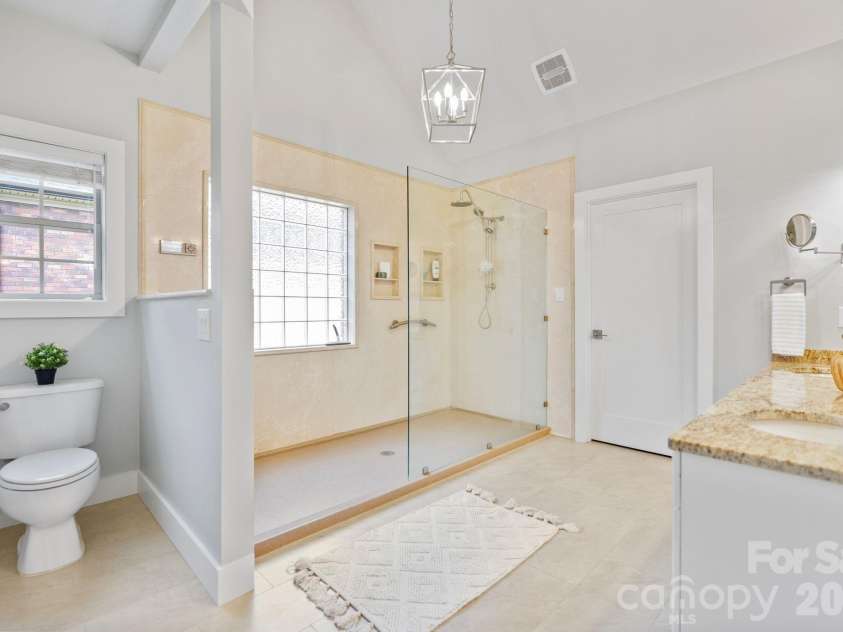 526 Ballymote Court, Matthews, NC 28104.  MLS# CAR4388258, YatesRealty ID 31207. Primary Bathroom – This spacious primary bath features a large walk-in shower with frameless glass enclosure, dual showerheads, and a glass block window that fills the space with soft natural light.