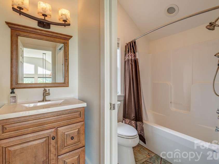 18 Adas Way, Weaverville, NC 28787.  MLS# CAR4385497, YatesRealty ID 31334. The guest bath is a quiet showpiece, adorned with striking fossilized wood tile that brings the warmth of the natural world indoors