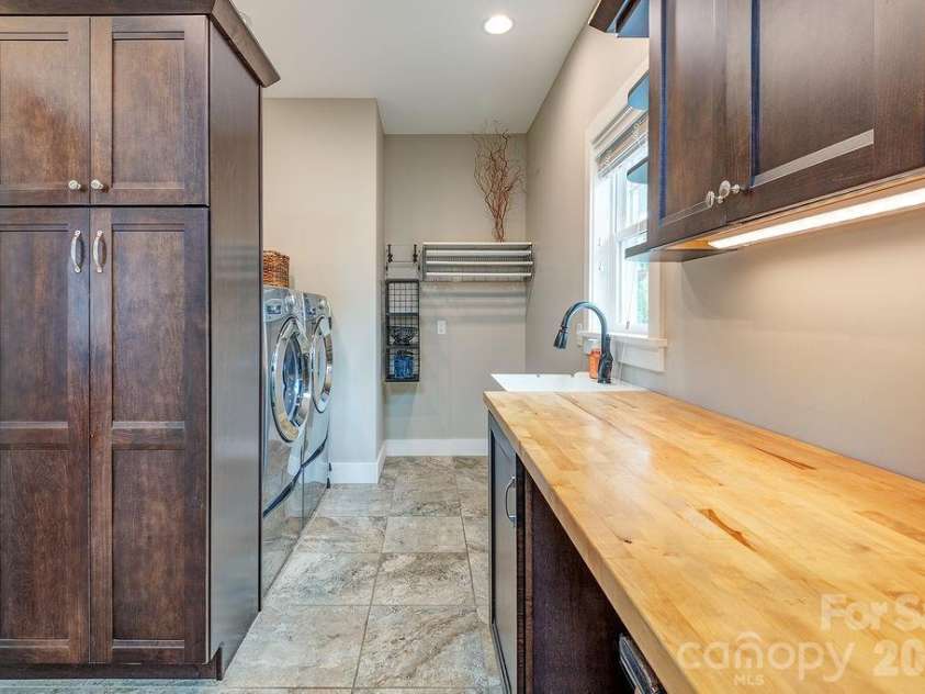 18 Adas Way, Weaverville, NC 28787.  MLS# CAR4385497, YatesRealty ID 31334. The laundry room and mudroom are bathed in natural light from the skylight above and include plenty of custom storage solutions, plus laundry machines on pedestals 