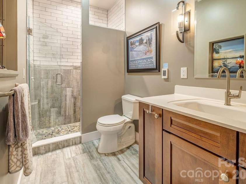 18 Adas Way, Weaverville, NC 28787.  MLS# CAR4385497, YatesRealty ID 31334. The lower level full bath is nothing short of a showstopper — radiant heated floors, floor-to-ceiling tile, and a stone knee bench elevate every moment spent here