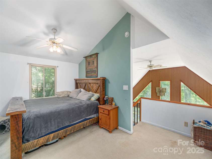 160 Tracy Place, Clyde, NC 28721.  MLS# CAR4282174, YatesRealty ID 31389. Bright loft-style bedroom with vaulted ceilings, wooded views, and an open overlook to the living area below