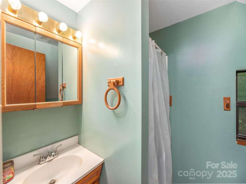 160 Tracy Place, Clyde, NC 28721.  MLS# CAR4282174, YatesRealty ID 31389. Bright loft-style bedroom with vaulted ceilings, wooded views, and an open overlook to the living area below