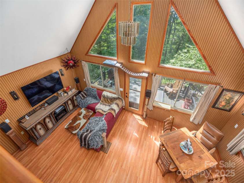 160 Tracy Place, Clyde, NC 28721.  MLS# CAR4282174, YatesRealty ID 31389. Dramatic two-story living area with soaring A-frame windows, rich wood accents, and abundant natural light, seamlessly opening to a private deck surrounded by nature
