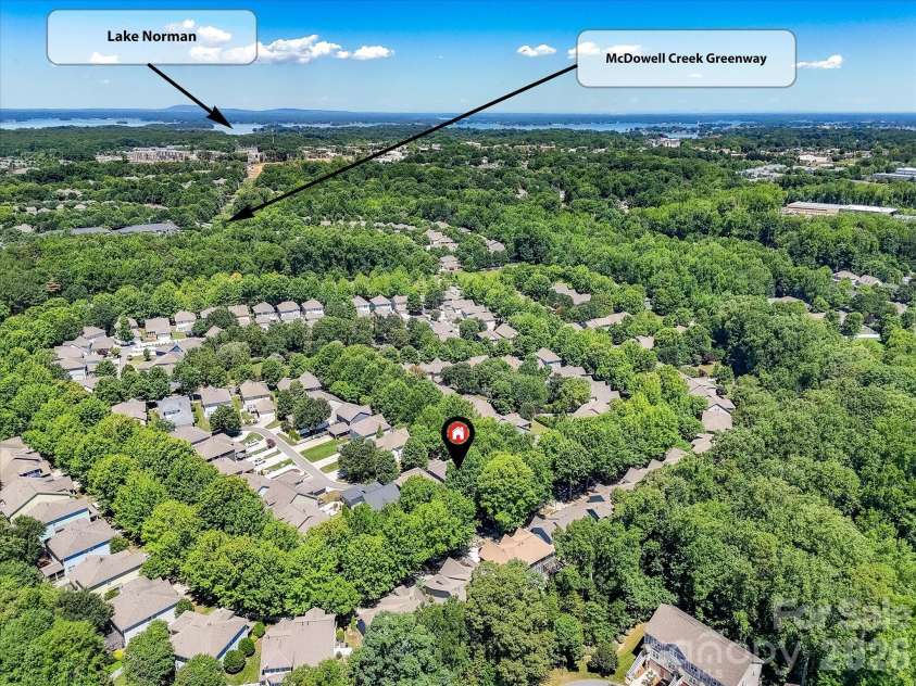 17404 Harbor Walk Drive, Cornelius, NC 28031.  MLS# CAR4393057, YatesRealty ID 31396. An aerial view showcases the home's desirable location surrounded by mature trees, with convenient access to the McDowell Creek Greenway and just minutes from the shores of Lake Norman.
