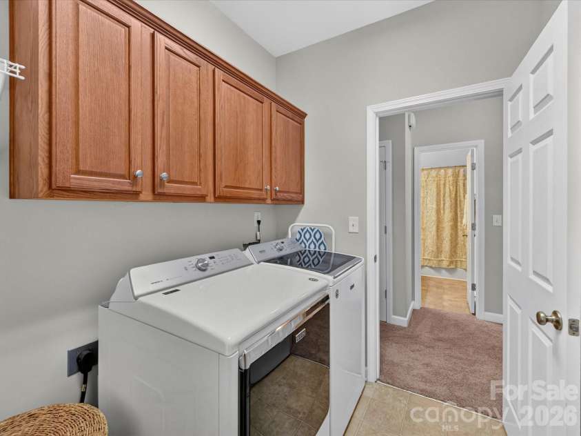 17404 Harbor Walk Drive, Cornelius, NC 28031.  MLS# CAR4393057, YatesRealty ID 31396. The dedicated laundry room features upper storage cabinetry, durable tile flooring, and convenient access to the upstairs living spaces for everyday ease.
