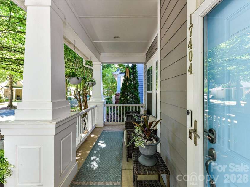 17404 Harbor Walk Drive, Cornelius, NC 28031.  MLS# CAR4393057, YatesRealty ID 31396. The inviting covered front porch offers a peaceful place to relax with comfortable seating, classic architectural details, and charming views of the tree-lined neighborhood.