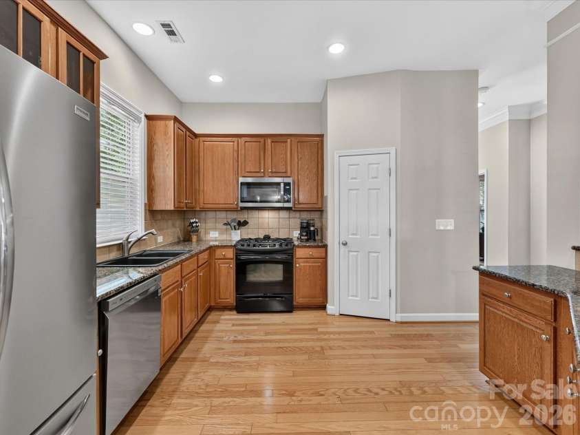 17404 Harbor Walk Drive, Cornelius, NC 28031.  MLS# CAR4393057, YatesRealty ID 31396. The spacious kitchen is designed for both everyday living and entertaining, featuring abundant cabinetry, granite countertops, stainless steel appliances, a breakfast bar, pantry, and a sunny dining area filled wit