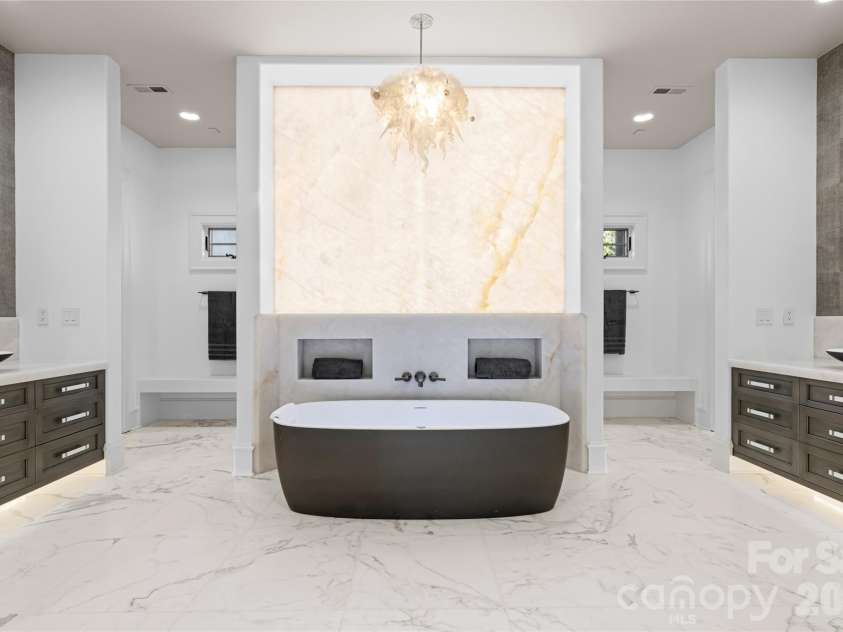 316 Braeside Court, Asheville, NC 28803.  MLS# CAR4198099, YatesRealty ID 3143. The showpiece of the owners suite is the backlit cristallo quartzite wall and custom-made hand-blown glass chandelier by Sam Stark that sets the tone of the his and hers bathroom!