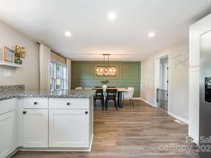 754 Rubens Road, Concord, NC 28027.  MLS# CAR4283491, YatesRealty ID 31457. This photograph showcases the seamless flow from the kitchen into the dining area, highlighting the open and inviting nature of the space. The warm, natural light streaming through the windows beautifully illuminates the roo