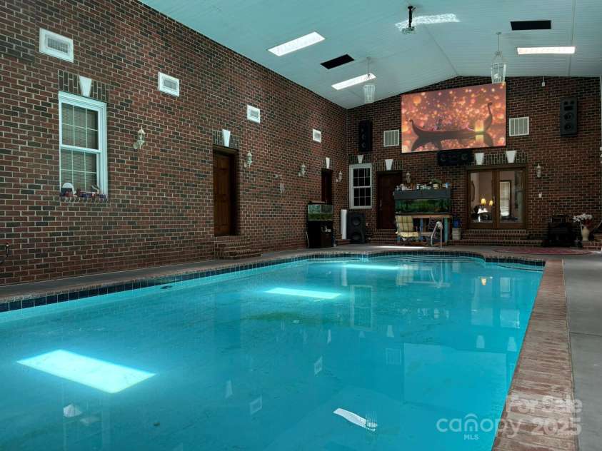 4900 Rocky River Road, Charlotte, NC 28215.  MLS# CAR4283934, YatesRealty ID 31470. Indoor pool showing large screen for TV viewing.