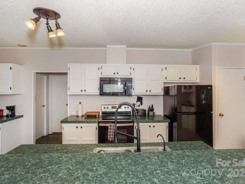 136 Buttercup Drive, Mooresville, NC 28117.  MLS# CAR4284193, YatesRealty ID 31853. Lots of room to cook or entertain family/guests with black appliances, SS sink, and lot of cabintry.