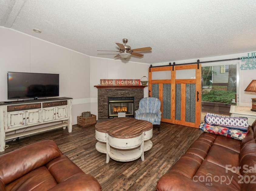136 Buttercup Drive, Mooresville, NC 28117.  MLS# CAR4284193, YatesRealty ID 31853. LVP flooring int the family room with gas fireplace and barn doors for privacy to the back deck.