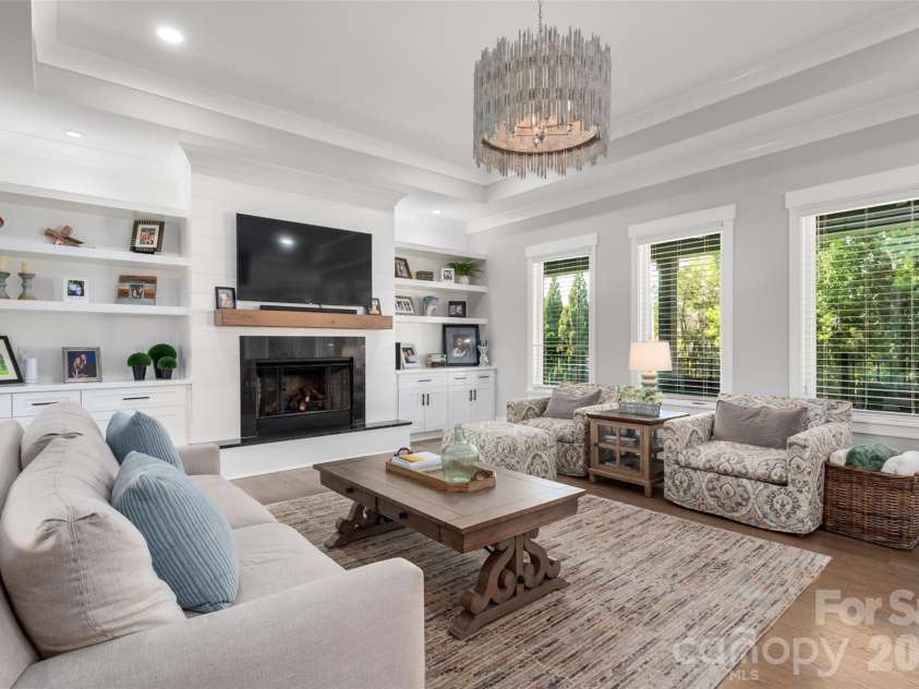 10035 Whispering Falls Avenue, Charlotte, NC 28227.  MLS# CAR4393646, YatesRealty ID 32047. The living room features a stunning fireplace flanked by custom built-ins, creating a warm and sophisticated focal point.