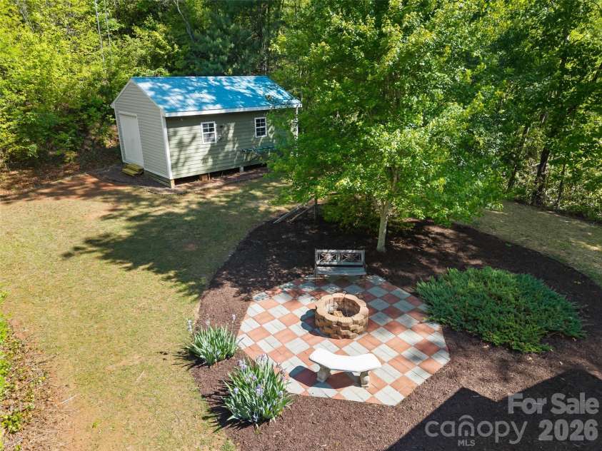 387 Crystal Creek Drive, Pisgah Forest, NC 28768.  MLS# CAR4373550, YatesRealty ID 32225. Side yard fire pit and outbuilding