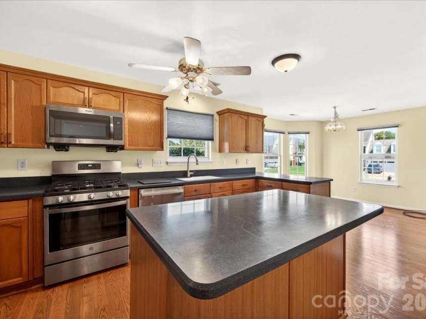 7716 Conifer Circle, Indian Trail, NC 28079.  MLS# CAR4389738, YatesRealty ID 32257. The light filled kitchen has plenty of counter space as well as a work island with Corian counters and newer stainless steel appliances.