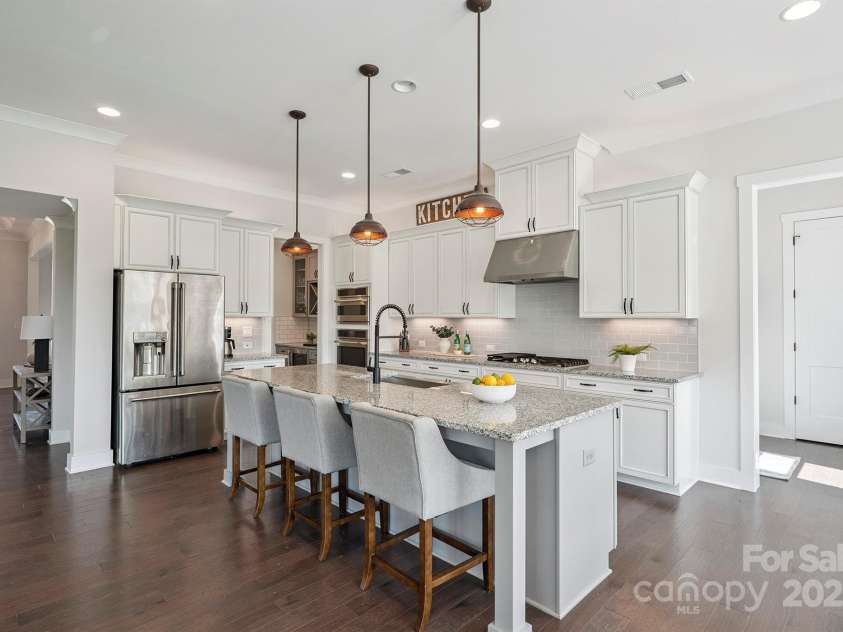 19012 Beecher Commons Drive, Huntersville, NC 28078.  MLS# CAR4276383, YatesRealty ID 32273. Gourmet Kitchen offers stainless steel appliances, granite counters, large center island with seating & storage, custom lighting including under cabinet, tile back splash, gas cook top, wall oven, butler's p