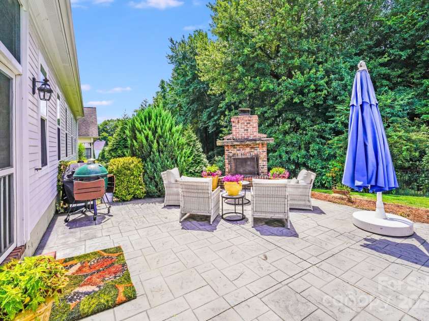 2702 Arsdale Road, Waxhaw, NC 28173.  MLS# CAR4287994, YatesRealty ID 32277. Expansive stamped concrete patio offers a seamless flow from indoor to outdoor living, complete with a built-in brick fireplace, vibrant landscaping, and ample space for grilling, relaxing, or entertaining