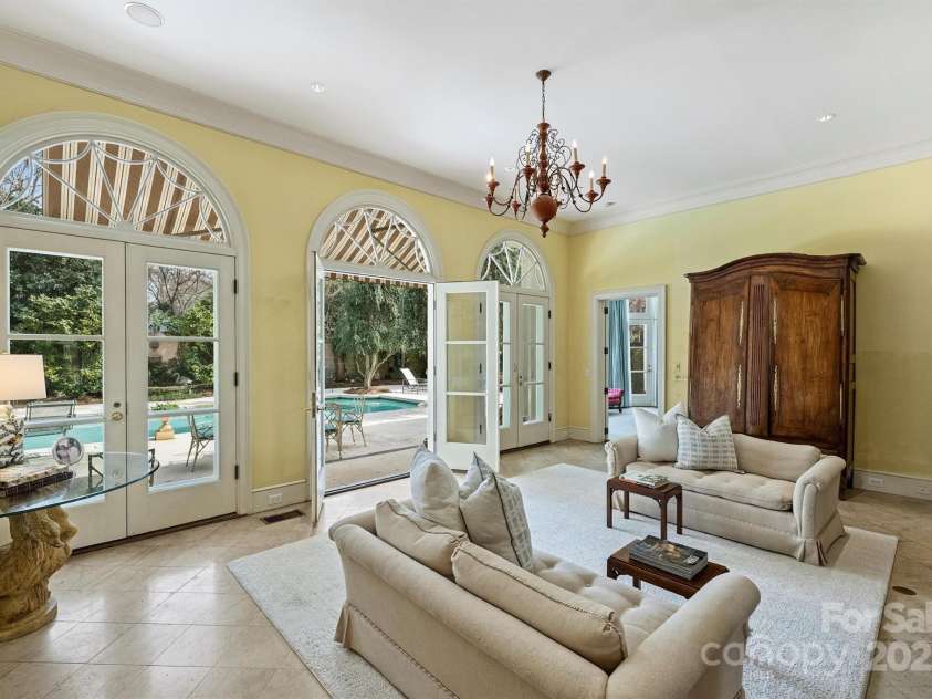 318 Canterbury Road, Charlotte, NC 28211.  MLS# CAR4231857, YatesRealty ID 3238. The sunroom, bathed in natural light, features three sets of French doors with fanlight windowed archways, opening to the serene garden and patio.
