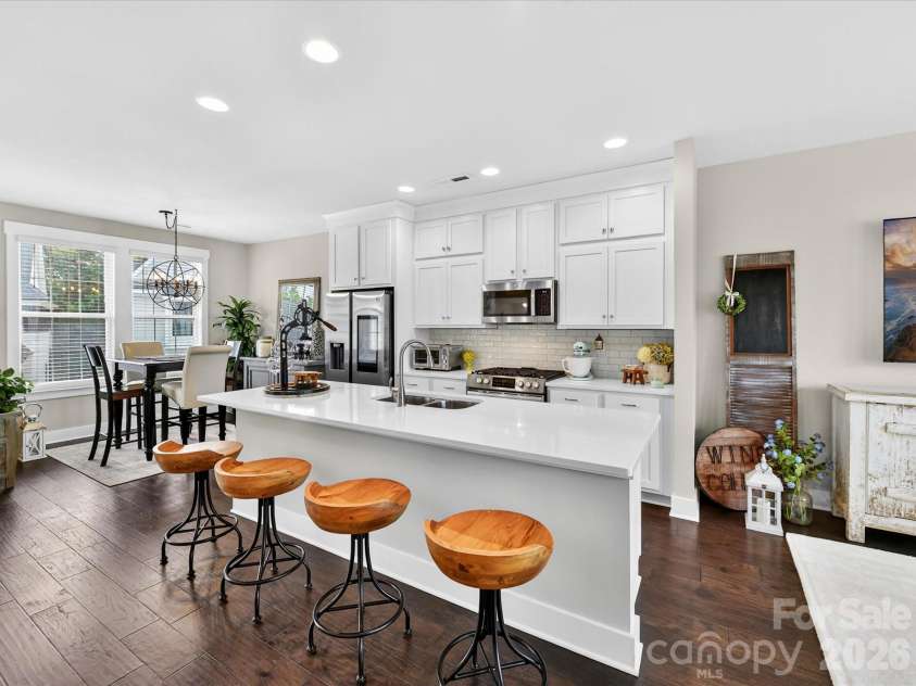 546 Amalfi Drive, Davidson, NC 28036.  MLS# CAR4390990, YatesRealty ID 32467. The beautifully appointed kitchen features quartz counters, crisp white shaker cabinetry, stainless steel appliances, a gas range, and an oversized island with seating, creating the perfect space for cooking, gathering, an