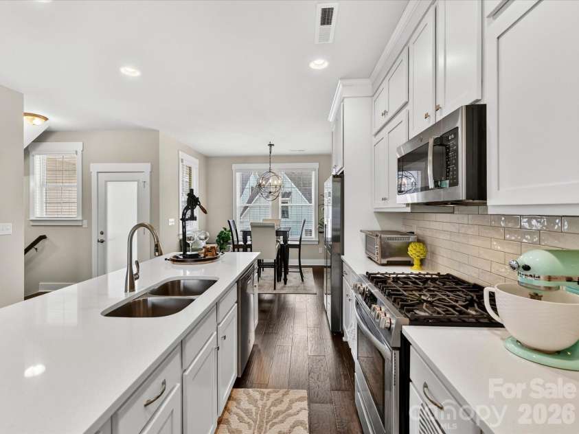 546 Amalfi Drive, Davidson, NC 28036.  MLS# CAR4390990, YatesRealty ID 32467. The beautifully appointed kitchen features quartz counters, crisp white shaker cabinetry, stainless steel appliances, a gas range, and an oversized island with seating, creating the perfect space for cooking, gathering, an