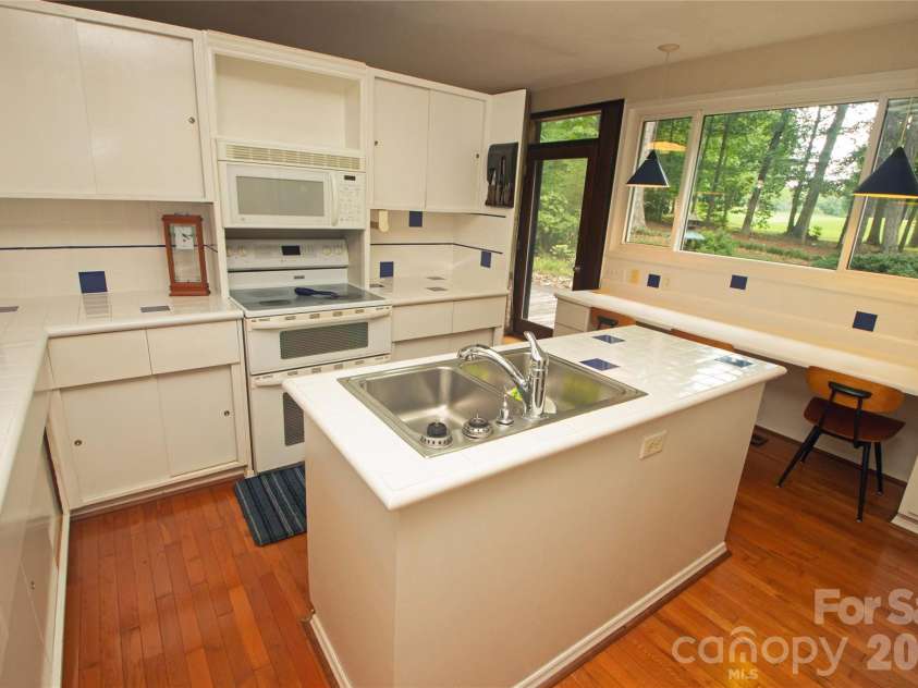 2638 Rolling Hills Drive, Monroe, NC 28110.  MLS# CAR4394198, YatesRealty ID 32619. The kitchen features tile countertops and backsplash, workspace island, range with double oven, and a breakfast bar that overlooks the rear yard.