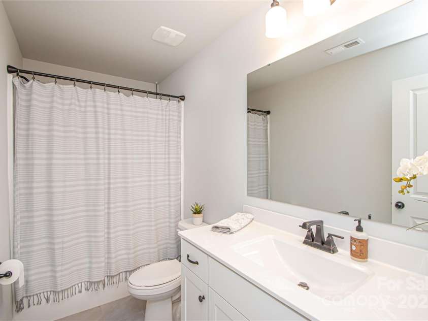 1061 Ansley Park Drive, Fort Mill, SC 29707.  MLS# CAR4281028, YatesRealty ID 32626. The hall bath features a white vanity with a quartz countertop and square sink, complemented by brushed nickel hardware and faucets.