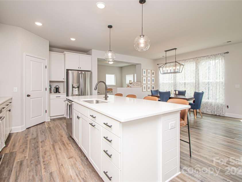 1061 Ansley Park Drive, Fort Mill, SC 29707.  MLS# CAR4281028, YatesRealty ID 32626. The kitchen features a large island, white cabinetry, quartz countertops, tile backsplash, stainless steel appliances, and brushed nickel hardware—perfectly blending style and function.