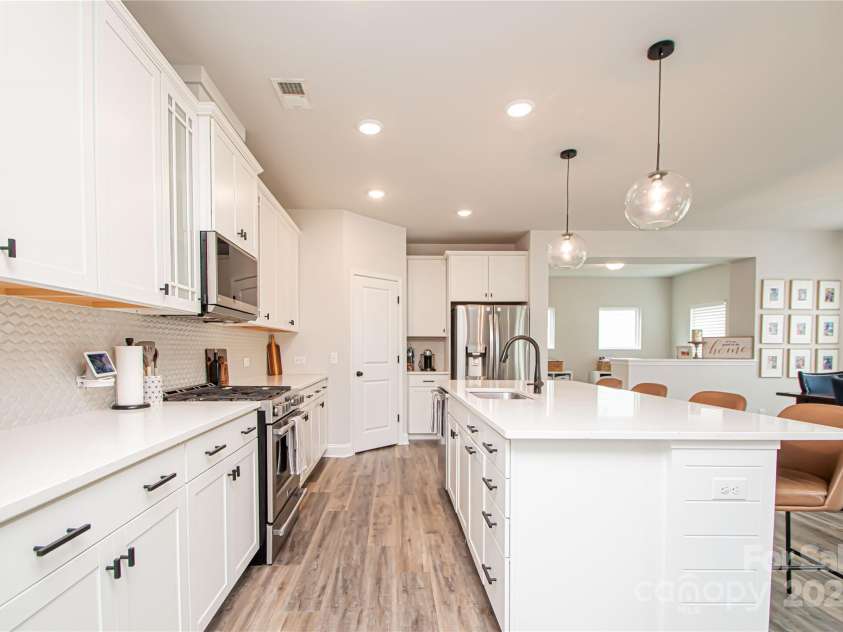 1061 Ansley Park Drive, Fort Mill, SC 29707.  MLS# CAR4281028, YatesRealty ID 32626. The kitchen features a large island, white cabinetry, quartz countertops, tile backsplash, stainless steel appliances, and brushed nickel hardware—perfectly blending style and function.
