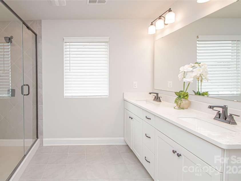 1061 Ansley Park Drive, Fort Mill, SC 29707.  MLS# CAR4281028, YatesRealty ID 32626. The primary bathroom features a spacious white vanity with dual square sinks, brushed nickel hardware and faucets, tile flooring, and an oversized walk-in shower.