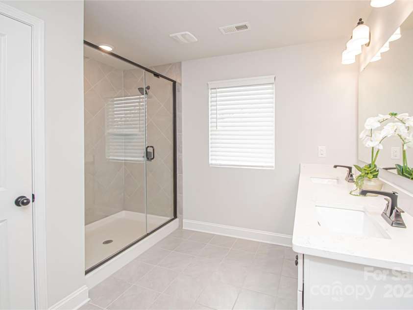 1061 Ansley Park Drive, Fort Mill, SC 29707.  MLS# CAR4281028, YatesRealty ID 32626. The primary bathroom features a spacious white vanity with dual square sinks, brushed nickel hardware and faucets, tile flooring, and an oversized walk-in shower.