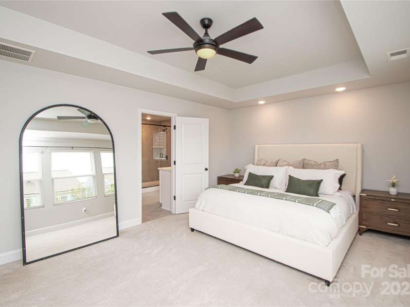 1061 Ansley Park Drive, Fort Mill, SC 29707.  MLS# CAR4281028, YatesRealty ID 32626. The spacious primary bedroom is located on the second floor and features a tray ceiling, ceiling fan with light kit, and large windows that fill the room with natural light.