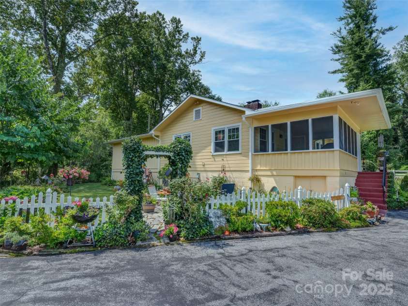 437 Rutledge Drive, Hendersonville, NC 28739.  MLS# CAR4286995, YatesRealty ID 32686. Backyard with multiple flowering plants.