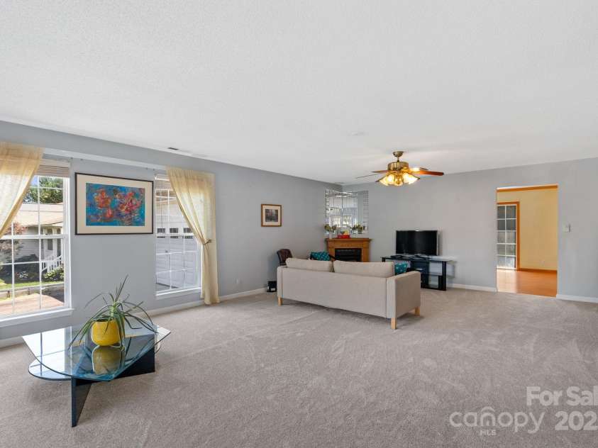 27 Eden Glen Road, Black Mountain, NC 28711.  MLS# CAR4292054, YatesRealty ID 3277. Expansive living room with abundant natural light, neutral tones, and a cozy fireplace focal point.