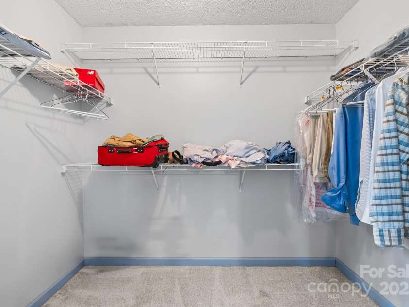 27 Eden Glen Road, Black Mountain, NC 28711.  MLS# CAR4292054, YatesRealty ID 3277. The primary suite is complete with a spacious walk-in closet, offering ample room for clothing, shoes, and accessories. With multiple hanging racks and shelving, it provides the organization and storage every homeown