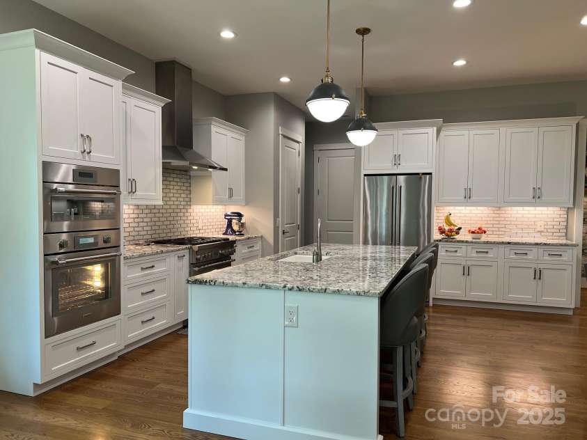 126 Redbud Lane, Troutman, NC 28166.  MLS# CAR4284135, YatesRealty ID 32890. On the back wall in this photo sits the refrigerator and more cabinets. There is an abundance of granite countertops for tons of workspace and serving areas.