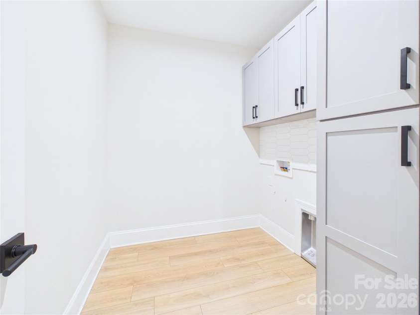 8027 Longwaters Court, York, SC 29745.  MLS# CAR4368751, YatesRealty ID 33228. This efficient laundry room features upgraded built-in cabinetry with sleek black hardware, offering ample storage solutions and a polished, custom look. The cabinetry is paired with a modern honeycomb tile backsplash and