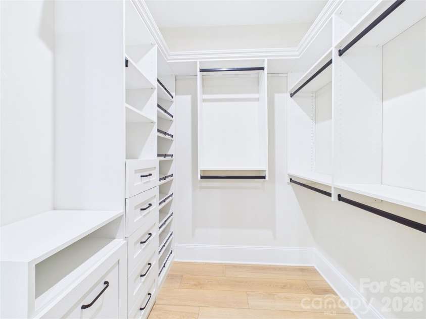 8027 Longwaters Court, York, SC 29745.  MLS# CAR4368751, YatesRealty ID 33228. This expansive walk-in closet features a custom-built organization system with floor-to-ceiling white shelving, drawers, and dedicated hanging space. The room is enhanced by a large built-in mirror that adds a sense of de