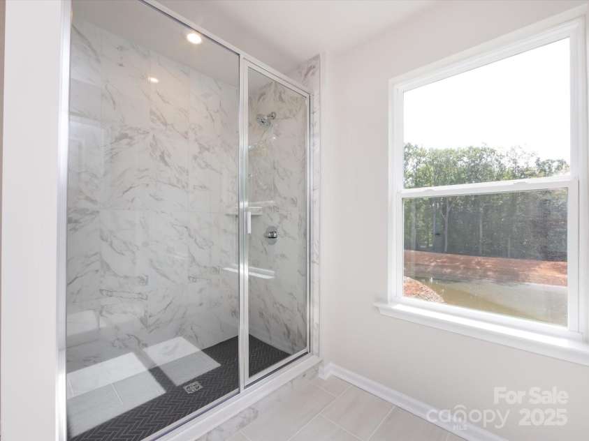 7023 Short Stirrup Lane, Mint Hill, NC 28227.  MLS# CAR4291701, YatesRealty ID 33286. Modern tiled primary walk-in shower and bright sunny window.