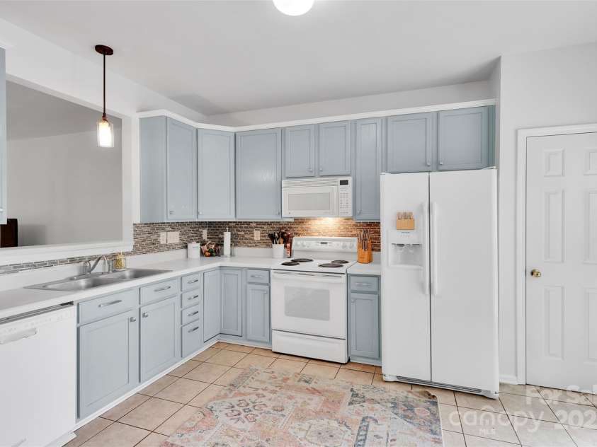 864 Tiger Lane, Charlotte, NC 28262.  MLS# CAR4278320, YatesRealty ID 33655. Cabinetry in a soft blue hue adds a pop of personality to this spacious kitchen, complete with tile backsplash, white appliances, and ample storage
