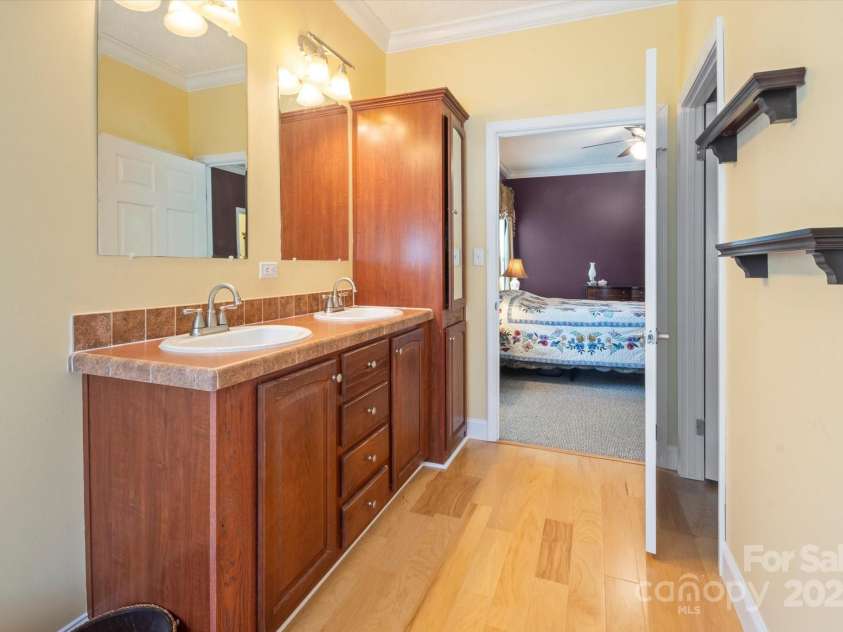 142 Pinners Cove Road, Asheville, NC 28803.  MLS# CAR4287127, YatesRealty ID 33723. Primary bathroom vanity looking into the bedroom with a large walk-in closet and water closet to the right.