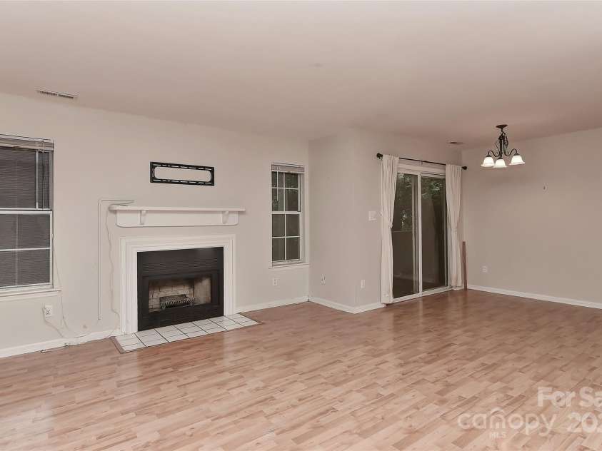 6500 Clavell Lane, Charlotte, NC 28210.  MLS# CAR4289455, YatesRealty ID 33760. Open living room w/wood burning fireplace and doors to private covered patio at/off dining area.