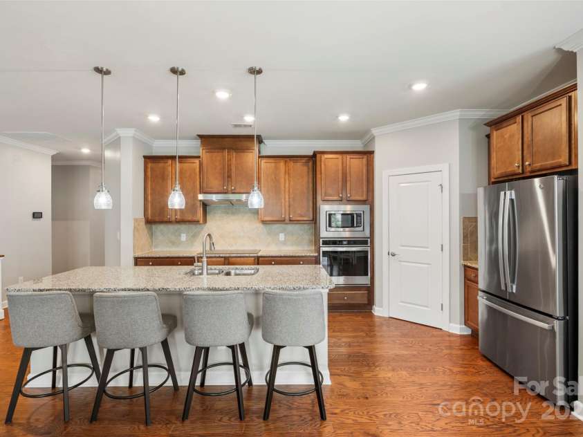5012 Laurel Glen Court, Monroe, NC 28110.  MLS# CAR4292898, YatesRealty ID 33778. Luxurious kitchen featuring a spacious island, walk-in pantry, sleek electric cooktop, and built-in wall/microwave oven—designed for both style and function