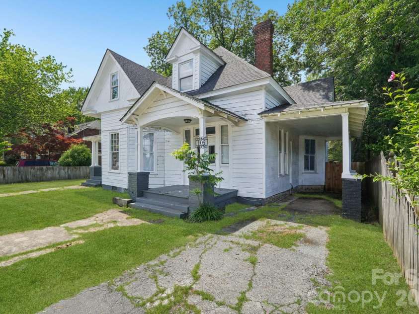 105 Houston Street, Monroe, NC 28112.  MLS# CAR4396106, YatesRealty ID 33807. Corner perspective showcasing the home's prominent setting, spacious yard, and inviting outdoor living spaces. Grass in photos has been digitally enhanced/improved for illustrative purposes.